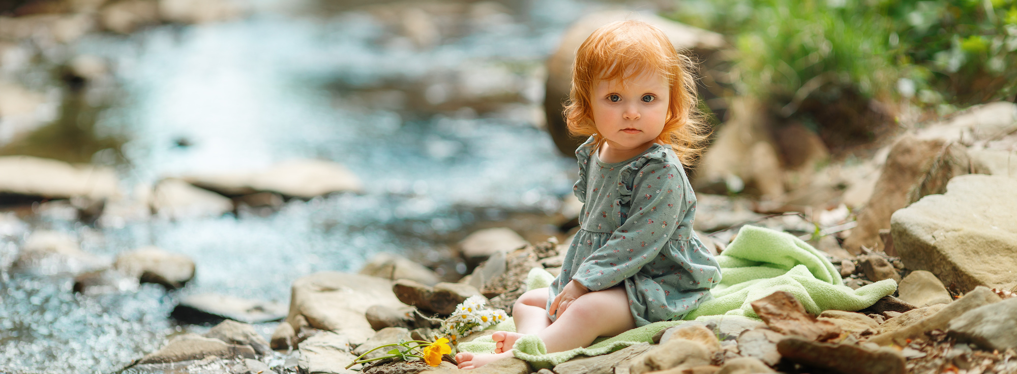 Cute little girl is sitting near the stream